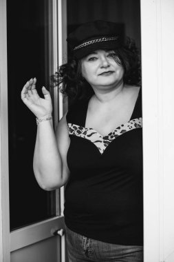 Orta yaşlı ve hayattan zevk alan iri yarı bir kadın. Aşırı kilolu, şık giyinmiş olgun bir bayan. Doğal güzellik.