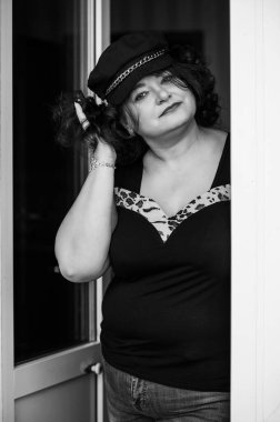 Orta yaşlı ve hayattan zevk alan iri yarı bir kadın. Aşırı kilolu, şık giyinmiş olgun bir bayan. Doğal güzellik.