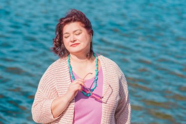 Orta yaşlı ve hayattan zevk alan iri yarı bir kadın. Aşırı kilolu, şık giyinmiş olgun bir bayan. Doğal güzellik.