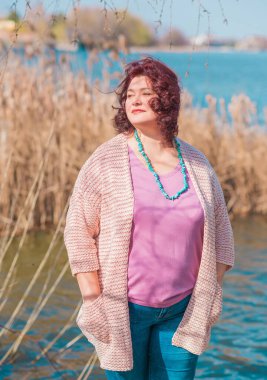 Orta yaşlı ve hayattan zevk alan iri yarı bir kadın. Aşırı kilolu, şık giyinmiş olgun bir bayan. Doğal güzellik.