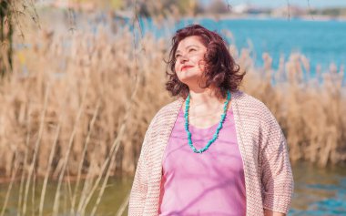 Orta yaşlı ve hayattan zevk alan iri yarı bir kadın. Aşırı kilolu, şık giyinmiş olgun bir bayan. Doğal güzellik.