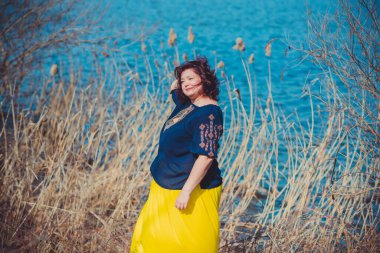 Orta yaşlı ve hayattan zevk alan iri yarı bir kadın. Aşırı kilolu, şık giyinmiş olgun bir bayan. Doğal güzellik.