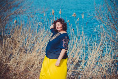 Orta yaşlı ve hayattan zevk alan iri yarı bir kadın. Aşırı kilolu, şık giyinmiş olgun bir bayan. Doğal güzellik.