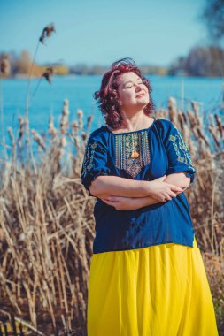 Orta yaşlı ve hayattan zevk alan iri yarı bir kadın. Aşırı kilolu, şık giyinmiş olgun bir bayan. Doğal güzellik.