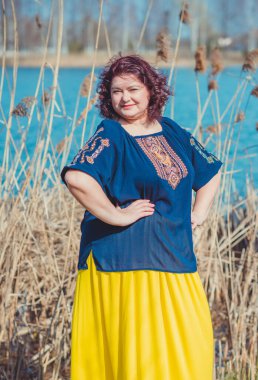 Orta yaşlı ve hayattan zevk alan iri yarı bir kadın. Aşırı kilolu, şık giyinmiş olgun bir bayan. Doğal güzellik.