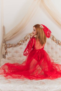 Tutkulu kızıl saçlı kadın yatak odasında kırmızı havadar bir elbise içinde romantik bir konsept, sevgililer günü, seksi iç çamaşırı.