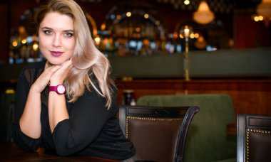 Sıcak atmosfer restoranında genç, zarif, iri yarı bir kadın. Bayan randevuyu romantik bir havada bekler. Kalın vintage tonlarda portre