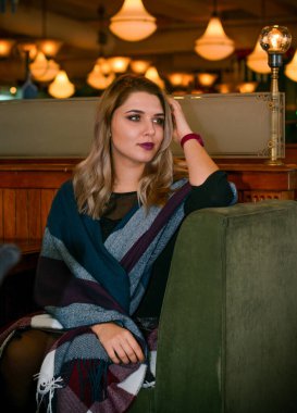 Sıcak atmosfer restoranında genç, zarif, iri yarı bir kadın. Bayan randevuyu romantik bir havada bekler. Kalın vintage tonlarda portre