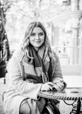 Sarı saçlı, cüsseli, sevimli, basit bir kadın. Alışverişte yürüyor, vitrinlere bakıyor. Alışveriş ve şık aksesuarlar gibi şeyleri seçiyor.