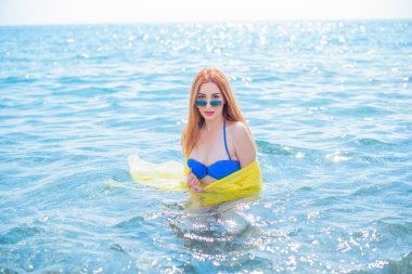   Kadın dinleniyor ve denizde eğleniyor. Tatilde iyi bir ruh hali, sıcak hava ve mutlu bir turist.