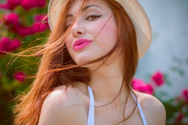 Tarlada açık tenli, güzel kızıl saçlı bir bakire, klasik modaya uygun giyinir. Bir kız çiçeklerin ve otların yanında dinleniyor güzelliğin tadını çıkarıyor.