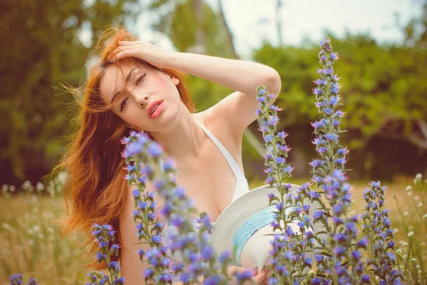一个美丽的红头发处女座 白皙的皮肤在田里被风格化了 一个女孩在花朵和香草旁边休息 享受美丽 — 图库照片