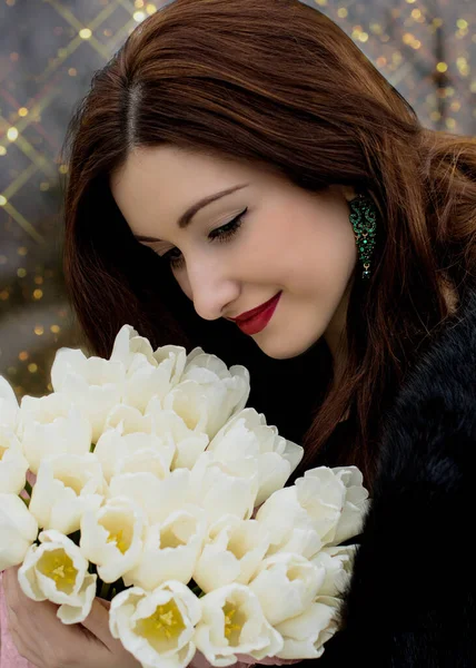 Gorgeous woman on a date at evening with vintage makeup and bouquet white tulips
