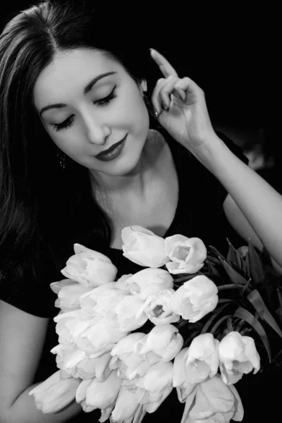 Gorgeous woman on a date at evening with vintage makeup and bouquet white tulips