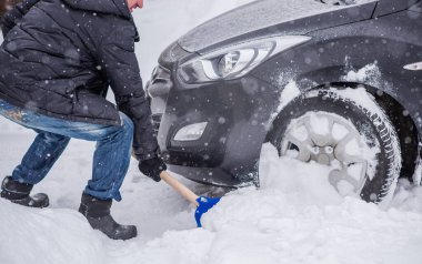 Kış, insanlar ve araba sorunu kavramı. Adam arabayı itmeye çalışıyor, karda sıkışıyor. Karşılıklı yardım. Kış sorunu. Ulaşım, Kış ve Araç Konsepti - Karda sıkışmış arabayı iten adama yakın çekim