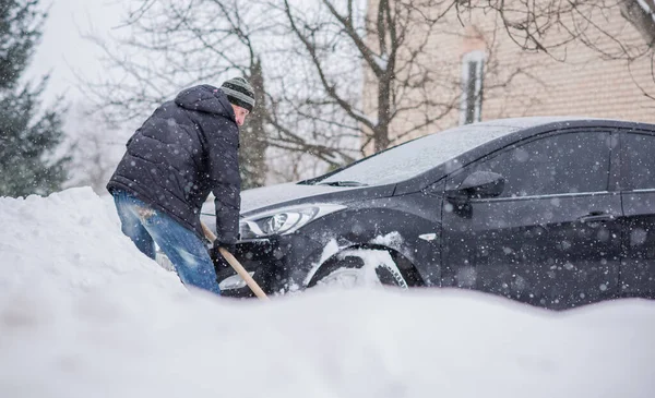 Winter, people and car problem concept. Man try on pushing the car, stuck in the snow. Mutual aid. Winter problem. transportation, winter and vehicle concept - closeup of man pushing car stuck in snow