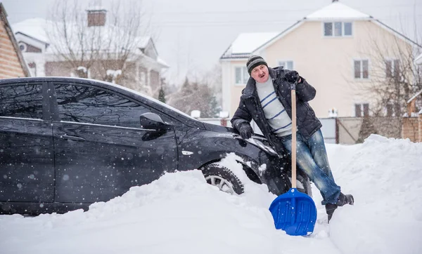 Winter, people and car problem concept. Man try on pushing the car, stuck in the snow. Mutual aid. Winter problem. transportation, winter and vehicle concept - closeup of man pushing car stuck in snow