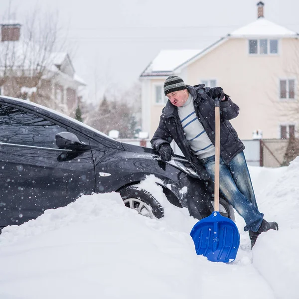 Winter, people and car problem concept. Man try on pushing the car, stuck in the snow. Mutual aid. Winter problem. transportation, winter and vehicle concept - closeup of man pushing car stuck in snow