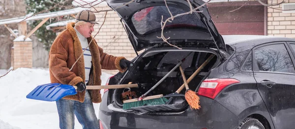 Winter, people and car problem concept. Man try on pushing the car, stuck in the snow. Mutual aid. Winter problem. transportation, winter and vehicle concept - closeup of man pushing car stuck in snow