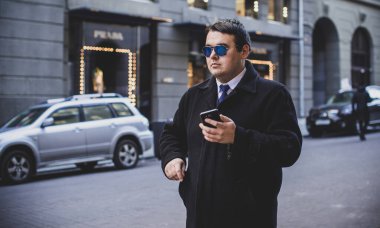 Şehir sokaklarında genç ve cüsseli bir adam, tombul insanlar konsepti, büyük şehir hayatı. Şehir merkezindeki şişman iş adamının görüntüsü