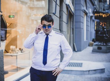 Şehir sokaklarında üniformalı genç ve cüsseli bir adam, tombul insanlar konsepti, büyük şehir hayatı.