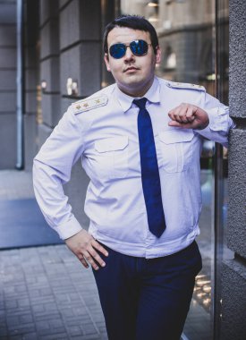 Şehir sokaklarında üniformalı genç ve cüsseli bir adam, tombul insanlar konsepti, büyük şehir hayatı.