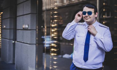 Şehir sokaklarında üniformalı genç ve cüsseli bir adam, tombul insanlar konsepti, büyük şehir hayatı.