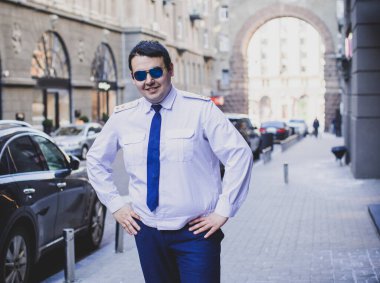 Şehir sokaklarında üniformalı genç ve cüsseli bir adam, tombul insanlar konsepti, büyük şehir hayatı.