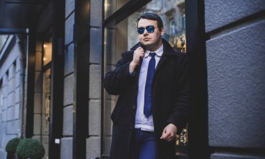 Şehir sokaklarında genç ve cüsseli bir adam, tombul insanlar konsepti, büyük şehir hayatı. Şehir merkezindeki şişman iş adamının görüntüsü