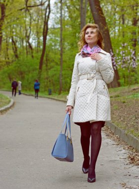 Bahar yürüyüşü, modaya uygun bir kadın parka bakıyor, modern kadın yaşam tarzı.