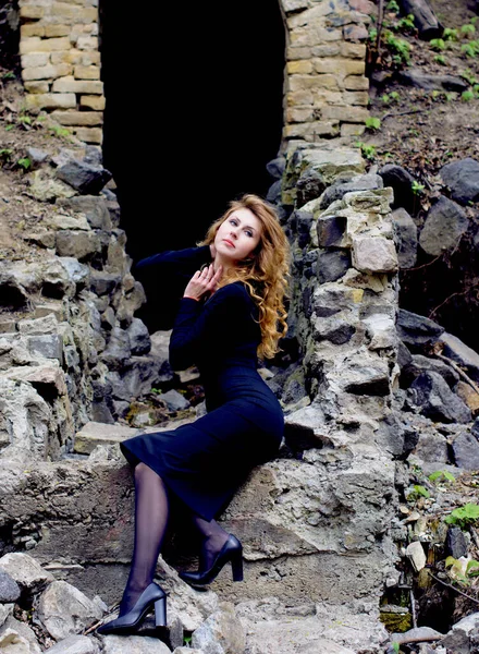 Beautiful sexy and elegant thin young light blonde european woman in total black dress and heels around old ruins in vintage style have a secret in her soul and finding the answer