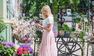Şık giyinen genç sarışın kadın şehir sokaklarında yürüyor, şık bir bayan, moda. Artı sokaktaki boy modeli.
