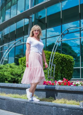 Şık giyinen genç sarışın kadın şehir sokaklarında yürüyor, şık bir bayan, moda. Artı sokaktaki boy modeli.