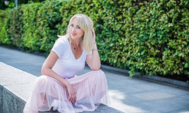 Şık giyinen genç sarışın kadın şehir sokaklarında yürüyor, şık bir bayan, moda. Artı sokaktaki boy modeli.