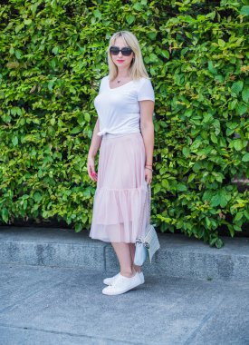 Şık giyinen genç sarışın kadın şehir sokaklarında yürüyor, şık bir bayan, moda. Artı sokaktaki boy modeli.