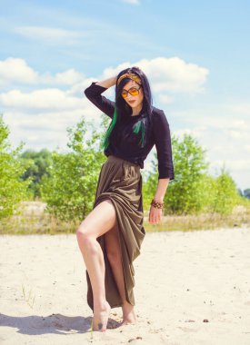 Hippi tarzı ve aksesuarlı genç hippi kadın kuma poz veriyor. Çingene görünümlü boho gezgin kız. Yaz seyahati. Atmosferik hareket ve yeşil kilitli şehvetli portre