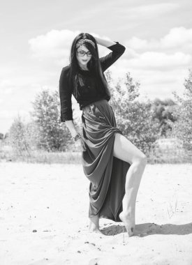 Hippi tarzı ve aksesuarlı genç hippi kadın kuma poz veriyor. Çingene görünümlü boho gezgin kız. Yaz seyahati. Atmosferik hareket ve yeşil kilitli şehvetli portre