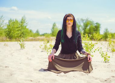 Hippi tarzı ve aksesuarlı genç hippi kadın kuma poz veriyor. Çingene görünümlü boho gezgin kız. Yaz seyahati. Atmosferik hareket ve yeşil kilitli şehvetli portre
