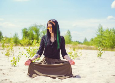 Hippi tarzı ve aksesuarlı genç hippi kadın kuma poz veriyor. Çingene görünümlü boho gezgin kız. Yaz seyahati. Atmosferik hareket ve yeşil kilitli şehvetli portre