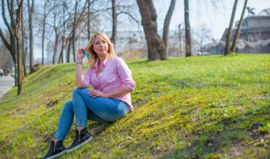 İlkbaharda şehir caddesinde yürüyen şık bir kadın. Sıradan moda, zarif görünüş. Artı boyut modeli. Şehrin sokaklarında yürüyen mutlu şişman kadın