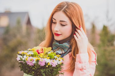 Açık havada çiçek buketi olan mutlu bir kadın. İyi ruh hali ve kadın yaşam tarzı konsepti