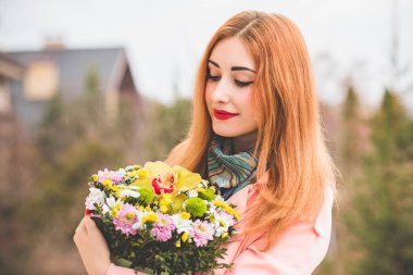 Açık havada çiçek buketi olan mutlu bir kadın. İyi ruh hali ve kadın yaşam tarzı konsepti