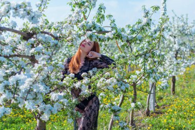 Bahar çiçekleri bahçesinde dantel elbiseli romantik bir kadın. Şefkat ve modern kadınlık kavramı