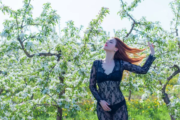 Bahar çiçekleri bahçesinde dantel elbiseli romantik bir kadın. Şefkat ve modern kadınlık kavramı