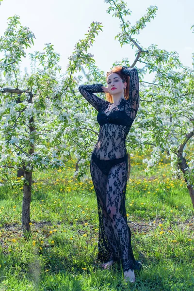 Bahar çiçekleri bahçesinde dantel elbiseli romantik bir kadın. Şefkat ve modern kadınlık kavramı