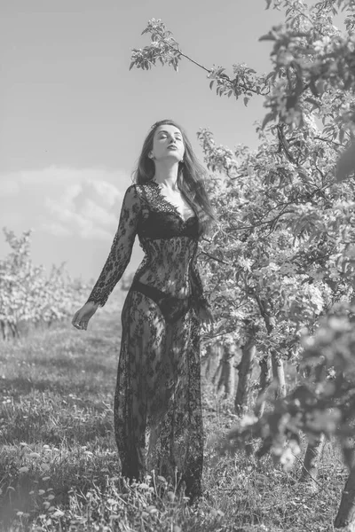 Bahar çiçekleri bahçesinde dantel elbiseli romantik bir kadın. Şefkat ve modern kadınlık kavramı