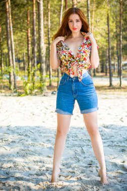 Akşamları, orman, kayalar ve suyun etrafında, kızıl saçlı güzel bir bayan. Klasik tarzda bir portre. Tatlı kadın denizde dinleniyor. Doğada tatil.