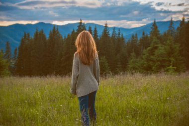 Tatil konsepti. Neşeli kadın uçurumun kenarında dinleniyor ve vadiye ve dağlara bakıyor. Dağlarda seyahat, özgürlük ve aktif yaşam tarzı konsepti