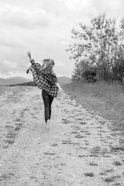 Tatil konsepti. Neşeli kadın uçurumun kenarında dinleniyor ve vadiye ve dağlara bakıyor. Dağlarda seyahat, özgürlük ve aktif yaşam tarzı konsepti