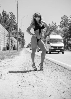 Formda, bikinili zayıf bir kadın yolda. Otostop konsepti